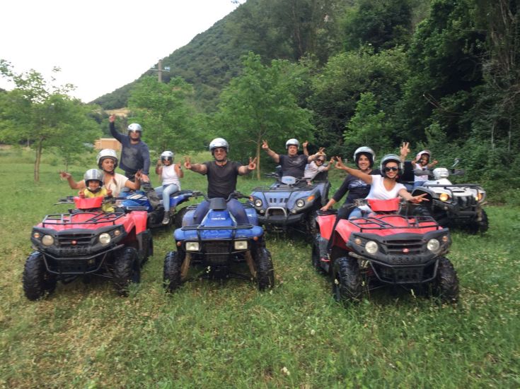 Un gruppo di amici si diverte a guidare quad in un paesaggio verde e naturale.