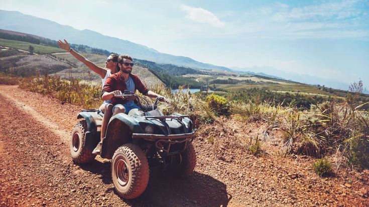 Una coppia si gode una passeggiata in quad attraverso piacevoli paesaggi naturali.