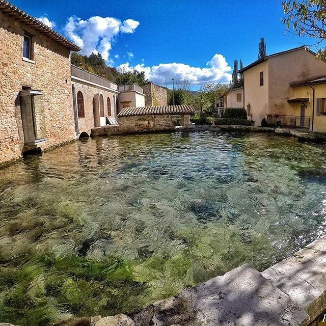 Una scena tranquilla con uno specchio d'acqua nel borgo di Rasiglia, circondato da edifici storici in Umbria.