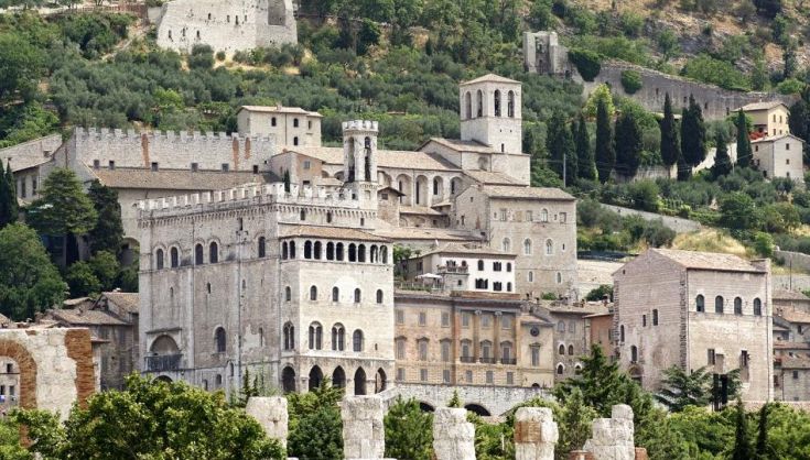Scena panoramica del centro storico di Gubbio, con edifici circondati dal verde della montagna Eugubina.
