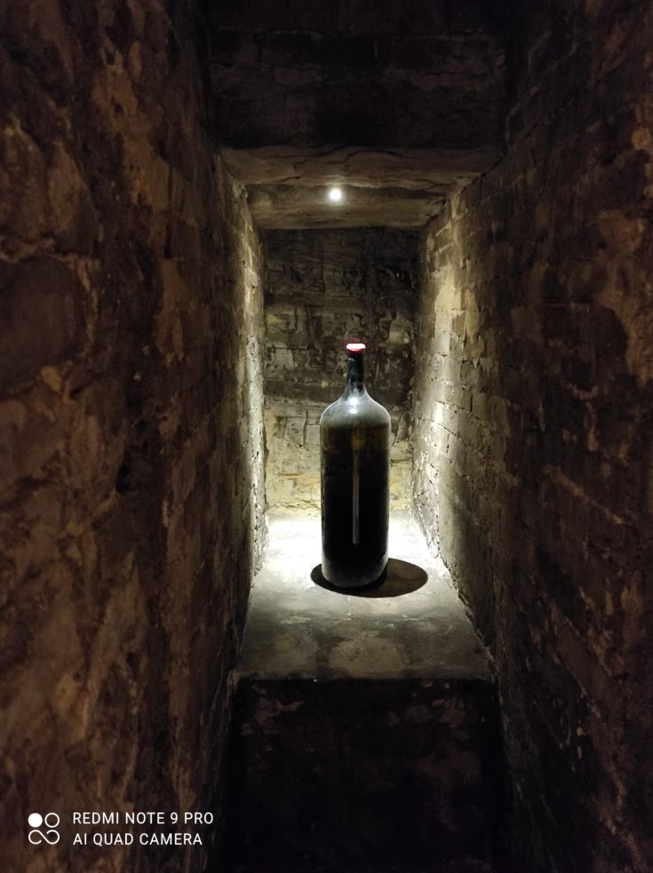 Una bottiglia scura illuminata in un vecchio palazzo di mattoni. L'atmosfera è discreta e tranquilla.