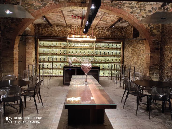 Interno sobrio di un locale con pareti in pietra e un lungo tavolo di legno.