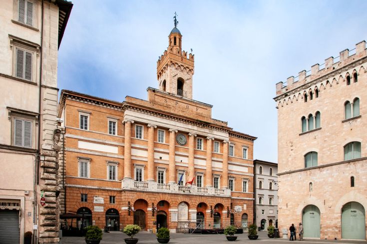 Il Palazzo Comunale di una storica cittadina umbra, caratterizzato da una muratura in mattoni e dettagli architettonici klassici.