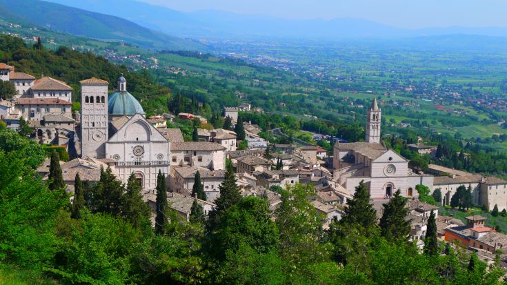 Panorama su un antico borgo in Umbria. Gli edifici storici dominano una valle verde e rigogliosa.