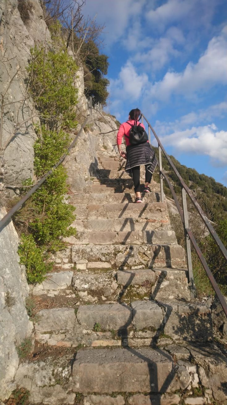 Una persona sale una scalinata in pietra circondata dalla natura.