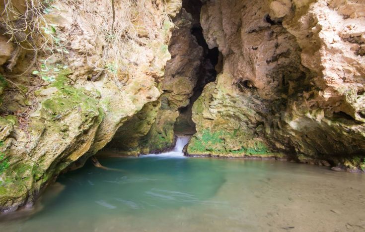 Una sorgente d'acqua in una grotta, circondata da un'atmosfera naturale e serena.
