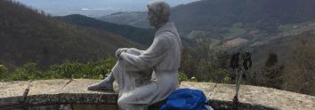 Una scultura in un ambiente naturale che si affaccia su valli verdi, immersa nella quiete del paesaggio.