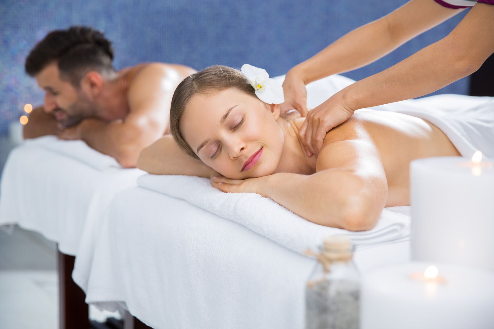 Due persone si stanno godendo un massaggio in un ambiente spa, circondate da candele.