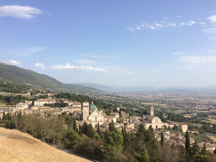 Scena di Assisi con i suoi antichi edifici e il paesaggio circostante tipico dell'Umbria.