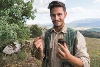 Un giovane uomo esplora la natura, mostrando un oggetto interessante trovato in un ambiente montano.