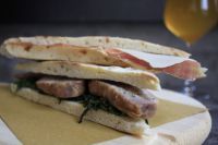 Un panino appetitoso preparato con carne fresca e verdure assortite, presentato su un semplice vassoio di legno.