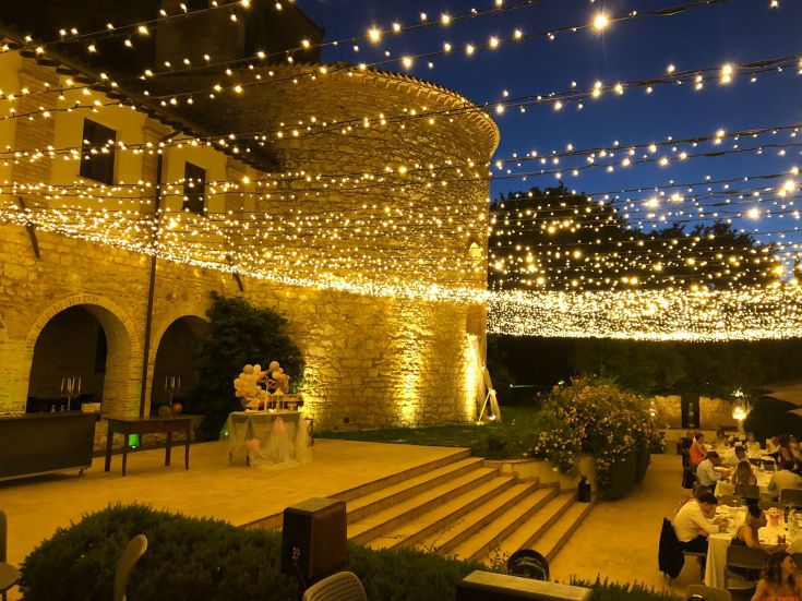 Un'atmosfera suggestiva durante un evento illuminato da luci brillanti, immerso nella storia e nella natura circostante.