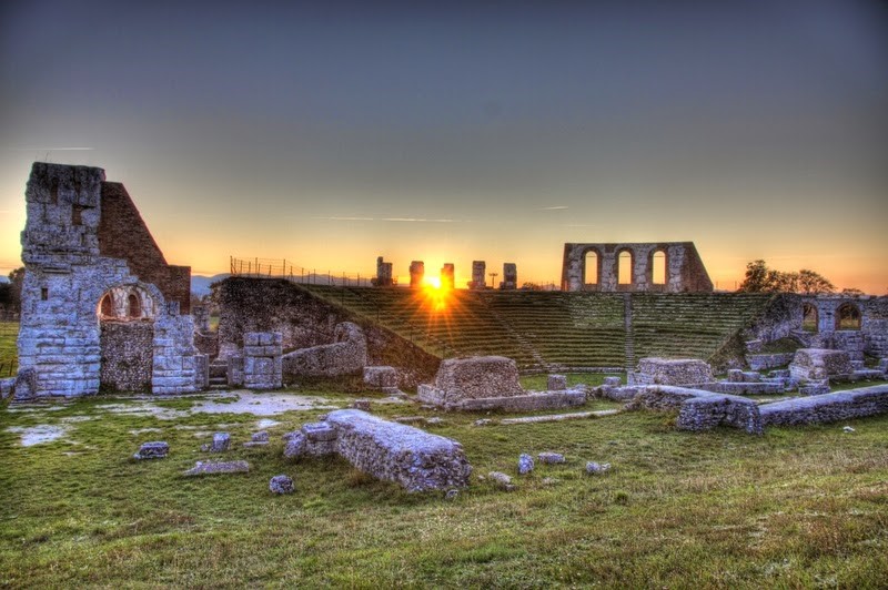 Teatro Romano di Gubbio al tramonto, immerso nella natura e testimone di un passato significativo.