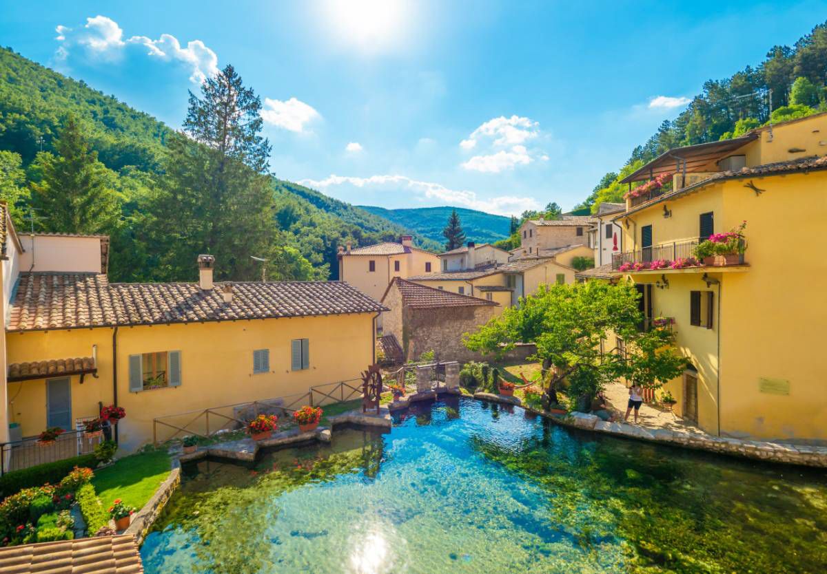 Un borgo caratteristico dell'Umbria, dove case gialle si trovano vicino a specchi d'acqua.