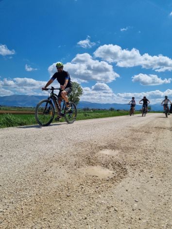 Un ciclista che pedala su una strada in pietra in Umbria, immerso nella natura.