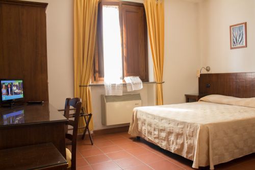 Camera accogliente in stile semplice, con TV, aria condizionata e panorama su un giardino.