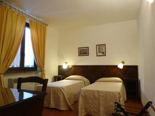 Una camera semplice con letti singoli e tende gialle, adatta per un soggiorno tranquillo.