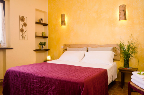 Camera con pareti gialle, decorazioni sobrie e letto matrimoniale, ideale per un soggiorno rilassante.