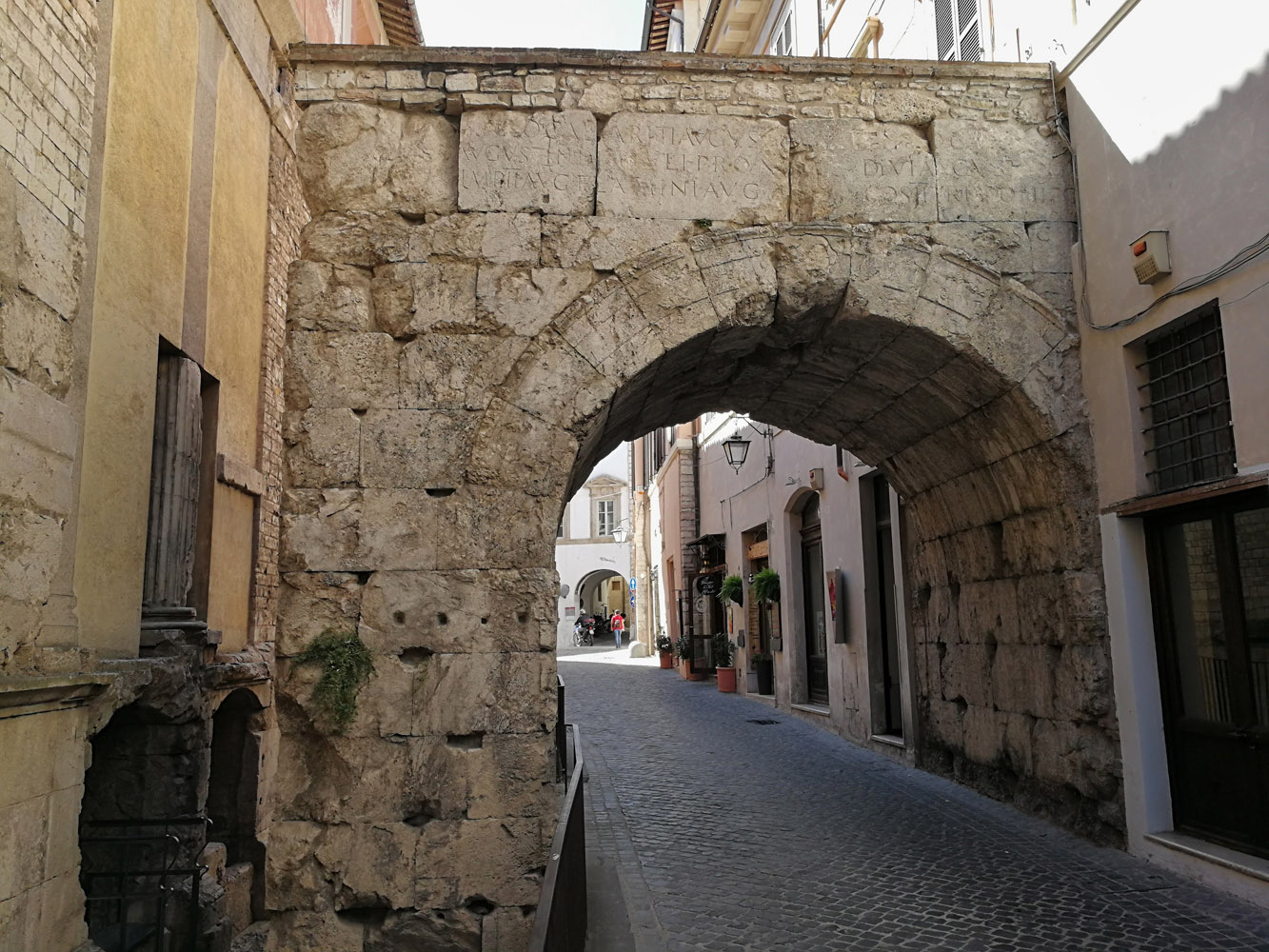 Un semplice arco in pietra che collega le strade di un borgo storico.