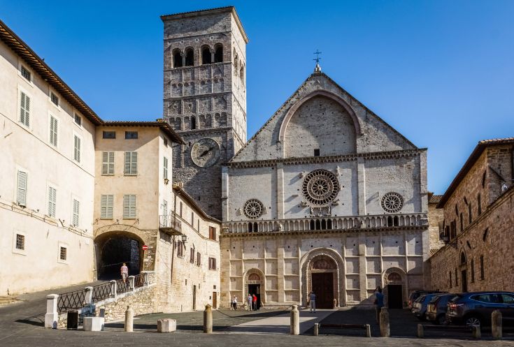 La facciata della cattedrale di San Rufino, circondata da edifici storici, rappresenta un luogo con una notevole eredità culturale.
