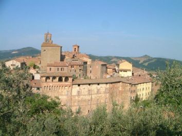 Scorcio di un borgo immerso nella natura umbra, con architettura storica e colline in lontananza.