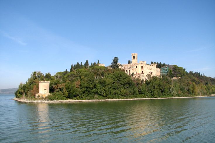 Un'isola verde con un palazzo antico che si affaccia su un lago tranquillo.