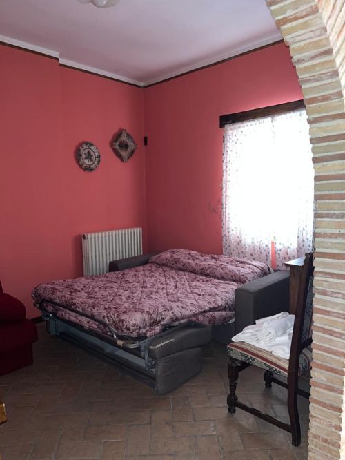Camera semplice con letto matrimoniale e tonalità calde, perfetta per una vacanza rilassante.