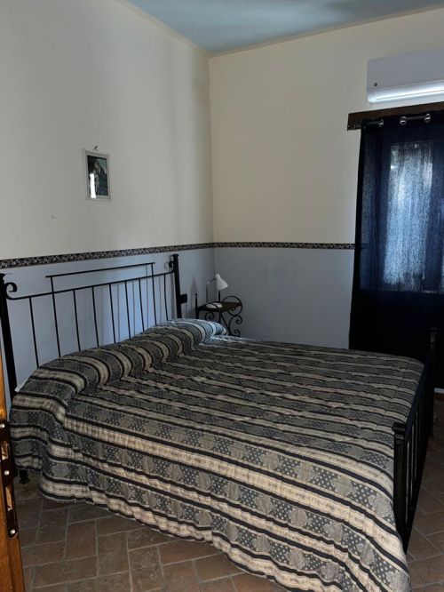 Camera semplice con letto matrimoniale e arredamento rustico, situata in una zona tranquilla.