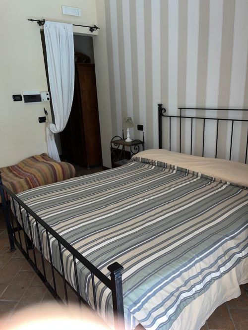 Camera confortevole in agriturismo, con letto matrimoniale e arredamento essenziale, circondata da un ambiente naturale.