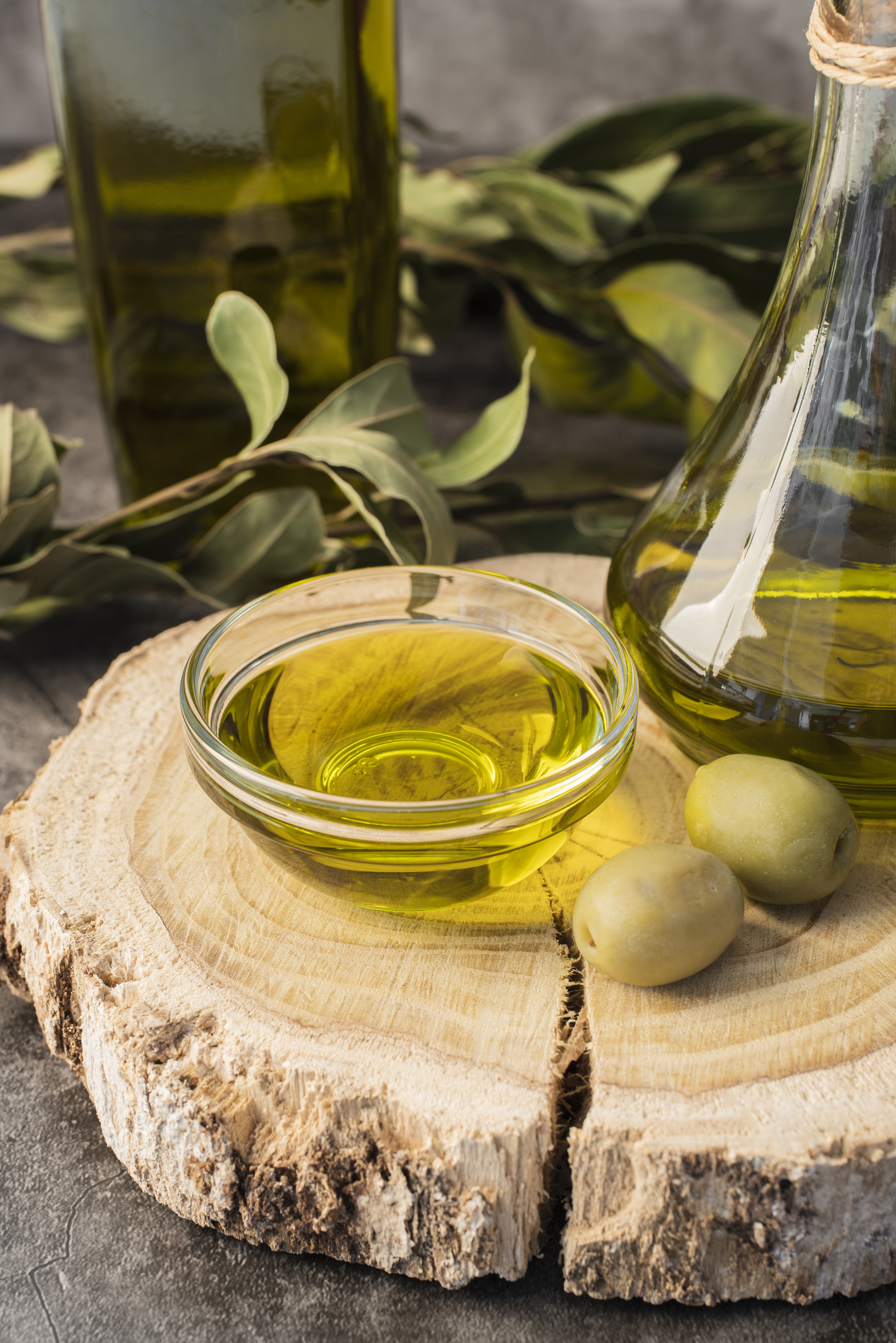 Una composizione di olio d'oliva di alta qualità e olive su un tagliere in legno, rappresentativa della tradizione culinaria italiana.