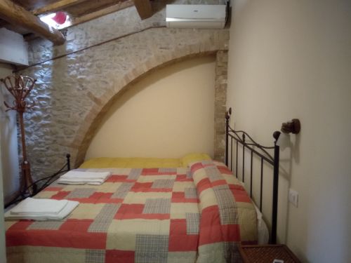 Una camera confortevole con letto e arredi in stile rustico, perfetta per un soggiorno tranquillo.