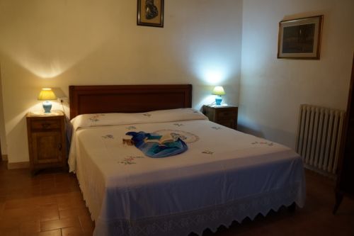 Camera semplice con letti, illuminazione delicata e arredi in legno.