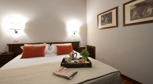 Camera spaziose con arredo semplice e funzionale, arricchita da elementi in legno e decorazioni discrete.