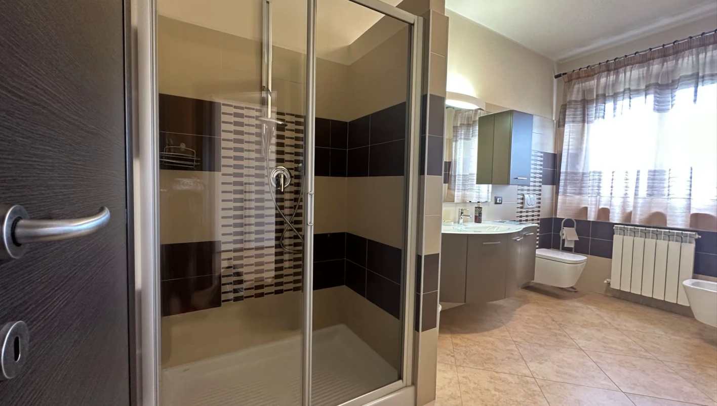 Bagno ben arredato e luminoso, dotato di una doccia spaziosa e di uno specchio, perfetto per momenti di relax.
