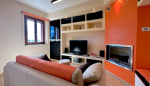 Soggiorno moderno e confortevole con area TV e camino, ideale per momenti di relax e svago.