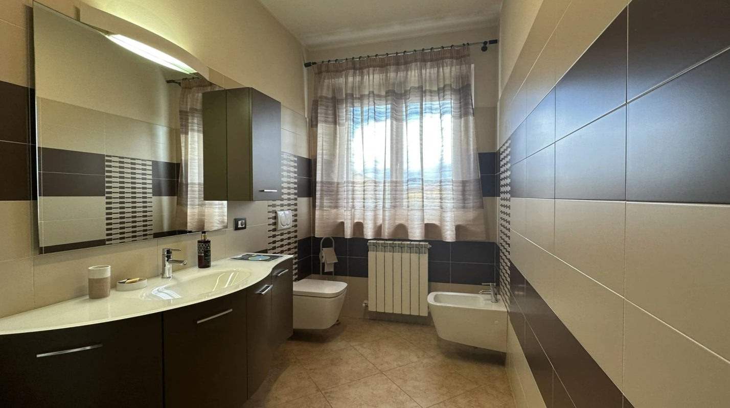 Bagno moderno con dettagli in tonalità marroni e pareti decorate. Spazio luminoso e accogliente.