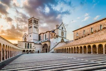 La Basilica di San Francesco ad Assisi, con i suoi archi e stili architettonici distintivi, si erge serene nel paesaggio circostante.