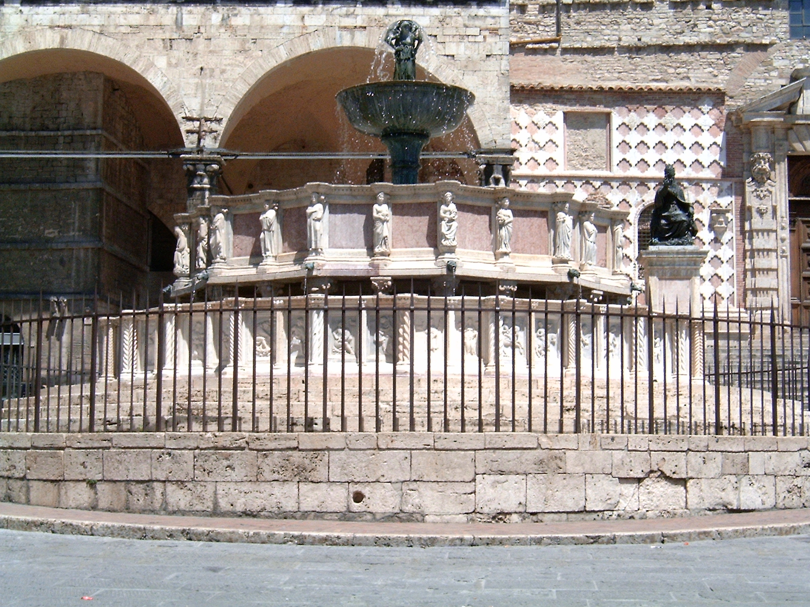 Una fontana situata in una piazza storica, circondata da statue e caratterizzata da elementi architettonici locali.