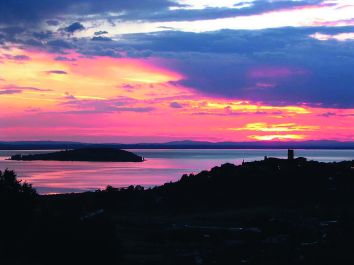 Un tramonto sul lago, con tonalità morbide di rosa e blu che si mescolano sulle acque calme.