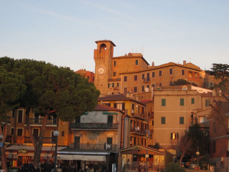 Una scena di un borgo umbro al tramonto, con case di pietra illuminate dalla calda luce serale.