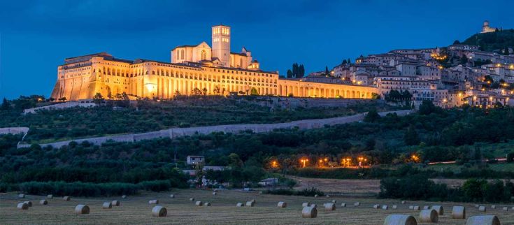 La Basilica di San Francesco illuminata al crepuscolo, un importante monumento storico in Umbria.