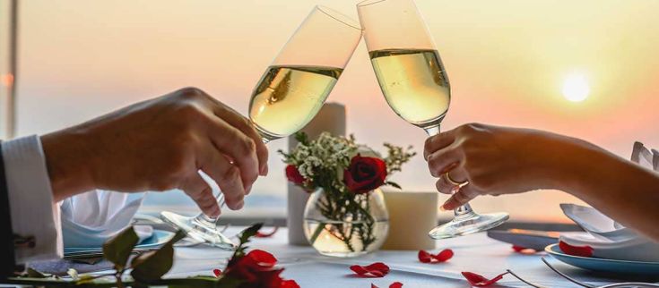 Due calici si incontrano per un brindisi romantico mentre il sole tramonta all'orizzonte.