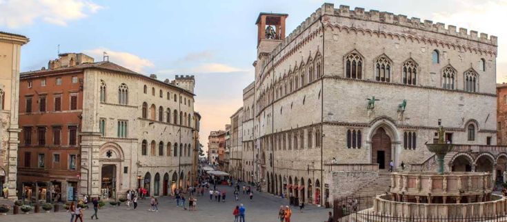 Scena del storico corso centrale di Perugia con edifici e la fontana maggiore, un luogo di ritrovo e di cultura.