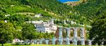 Un paesaggio dell'Umbria con rovine storiche immerse nel verde circostante.