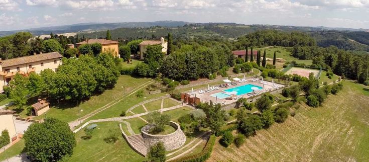 Un panorama di un resort in Umbria, immerso nel verde, con piscina e spazi per praticare sport.