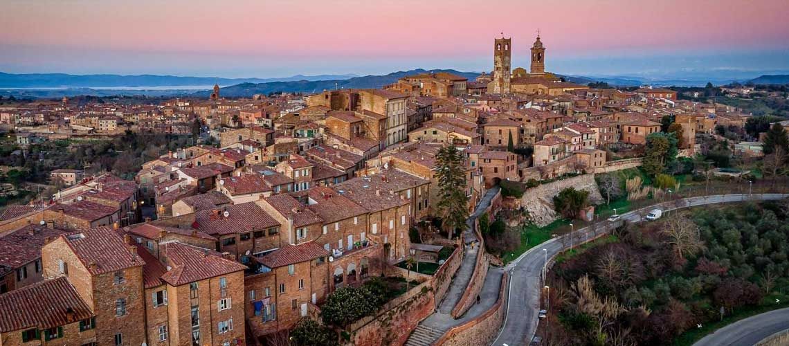 Scena di un borgo umbro al tramonto, con strade in pietra e torri che svettano nel cielo.