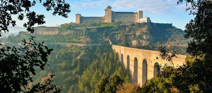 Rocca Albornoziana e ponte delle due Torri si ergono su una collina, circondato da verde e da un antico acquedotto.