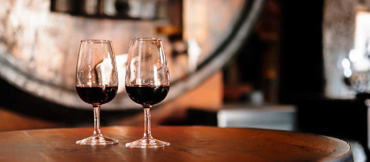 Due calici di vino rosso su un tavolo di legno, che creano un'atmosfera calda e accogliente.