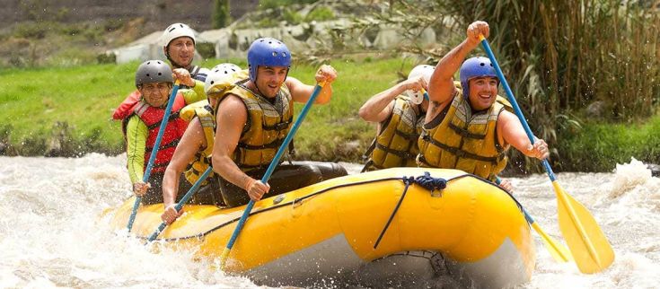 Un gruppo di amici si diverte facendo rafting su un fiume con forti correnti in Umbria.