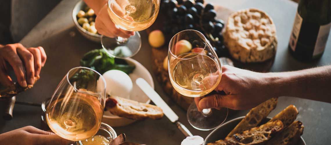 Un brindisi tra amici con bicchieri di vino, accompagnato da stuzzichini e un'atmosfera accogliente.